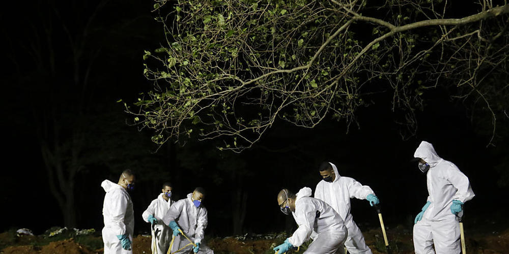 Friedhofsarbeiter senken den Sarg eines Covid-19-Opfers in sein Grab auf dem Friedhof Vila Formosa. Foto: Nelson Antoine/AP/dpa