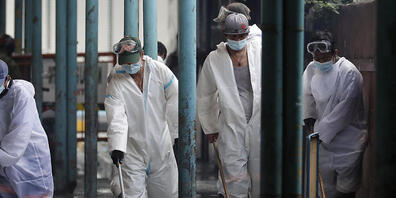 Arbeiter in Schutzanzügen desinfizieren einen Markt als Maßnahme gegen die Verbreitung des Coronavirus. Foto: Aaron Favila/AP/dpa