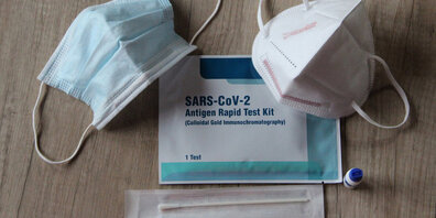 Ein Corona-Antigen-Schnelltestkit und zwei Schutzmaskenmodelle.