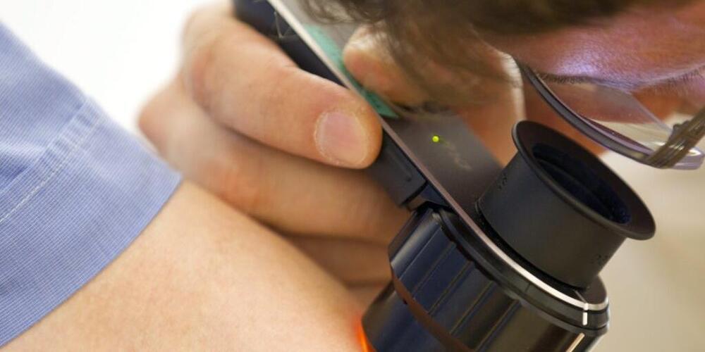 Ein Arzt untersucht einen Mann auf Hautkrebs. (Symbolbild)