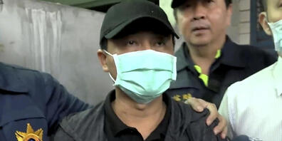 SCREENSHOT - Der Fahrer des Lastwagens, der ein Zugunglück verursacht hat, entschuldigt sich vor der Öffentlichkeit zwischen Polizisten. Foto: Uncredited/EBC/AP/dpa