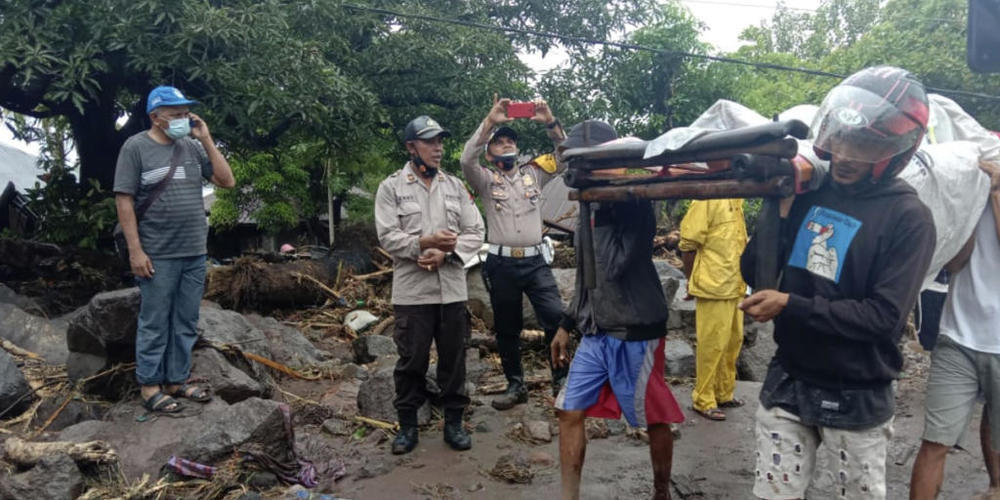 dpatopbilder - Menschen tragen einen Mann, der während einer Überschwemmung verletzt wurde. Foto: Ricko Wawo/AP/dpa