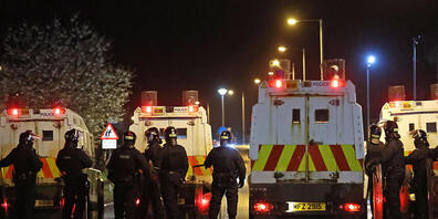 Polizisten stehen nach Unruhen auf einer Straße. In Nordirland ist es in der Osternacht erneut zu gewaltsamen Unruhen gekommen. Foto: Liam Mcburney/PA Wire/dpa