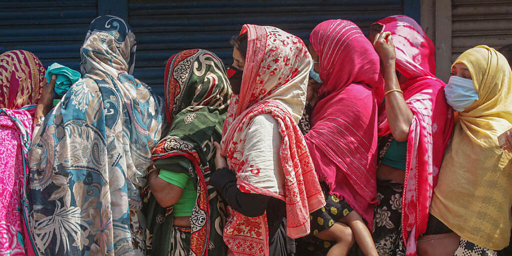 Frauen stehen gedrängt in einer Schlange, um Reis und Mehl auf dem offenen Markt zu kaufen. Ein landesweiter Lockdown hat für sieben Tage begonnen. Foto: Md Rafayat Haque Khan/ZUMA Wire/dpa