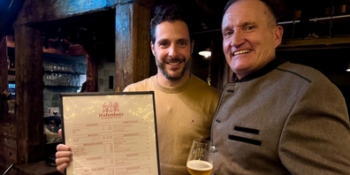 Michel Péclard und Geschäftspartner Florian Weber (li) von Pumpstation Gastro zeigen stolz die neue Speisekarte in Zusammenarbeit mit dem Guarda Val Lenzerheide.