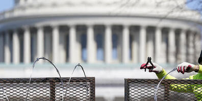 Ein Arbeiter entfernt den Stacheldraht von einem Sicherheitszaun auf dem Capitol Hill. Zweieinhalb Monate nach der Erstürmung des Kapitols durch Anhänger des damaligen US-Präsidenten Trump sind vier führende Mitglieder der rechtsradikalen Gruppe «...