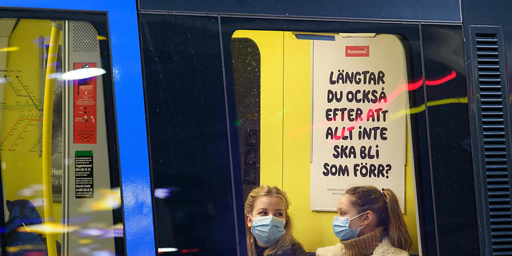 ARCHIV - Zwei Fahrgäste sitzen mit Mund-Nasen-Schutz in einer U-Bahn. Schweden hat auf die Bevölkerung gerechnet derzeit etwa dreimal so hohe Neuinfektionszahlen wie Deutschland - geplante Corona-Lockerungen dürften deshalb in dem skandinavischen ...