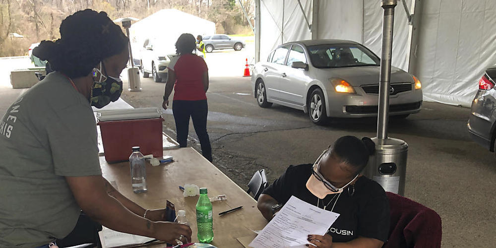 Mitarbeiterinnen einer Corona-Teststation organisieren ihren Arbeitsplatz. (Archivbild) Foto: Adrian Sainz/AP/dpa