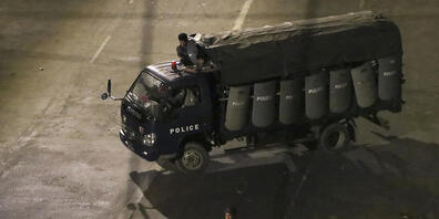 Polizisten sitzen in einem Lastwagen und fahren Patrouille in Yangon. Foto: Uncredited/AP/dpa