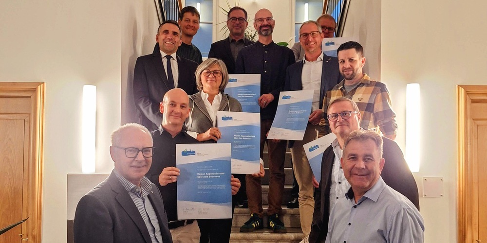 Dölf Biasotto, links, überbringt die besten Glückwünsche an Daniel Frunz, Präsident Fachgruppe Energiestadt-Region AüB und die Vertreter der sechs Gemeinden anlässlich der erfolgreichen Rezertifizierung