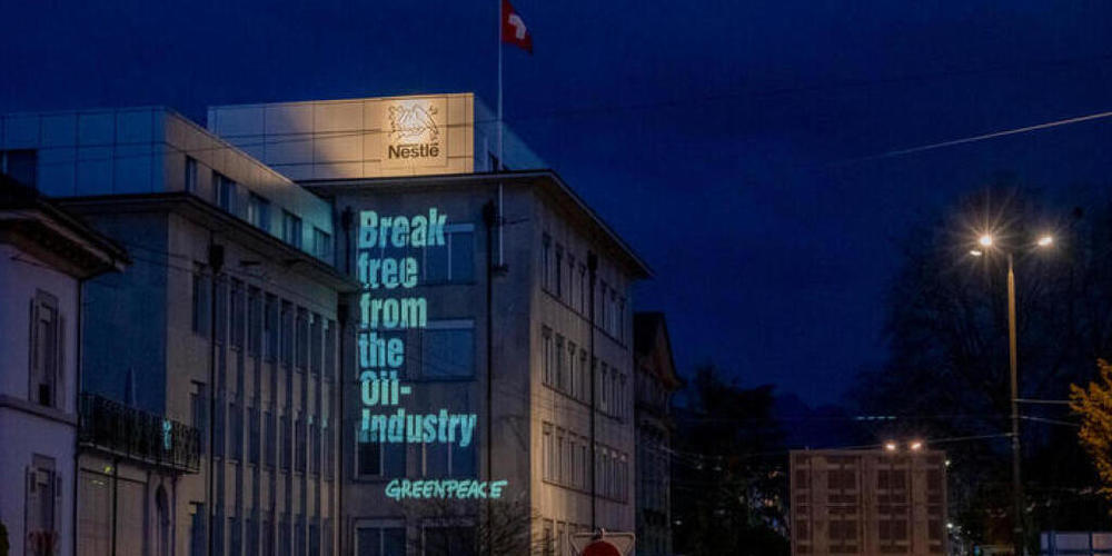 Die Umweltorganisation Greenpeace hat ihre Forderungen an die Fassade eines Nestlé-Betriebes in La-Tour-de-Peilz projeziert. (Bild: Greenpeace)