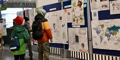 Eine Gruppe von Schülern betrachtet die Plakate auf dem Weg zur Garderobe.