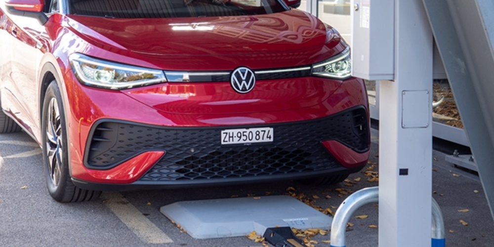 Ein umgerüstetes E-Auto lädt kabellos über die im Boden integrierte Spule – Der Ladevorgang startet automatisch, sobald das Fahrzeug korrekt parkiert ist.