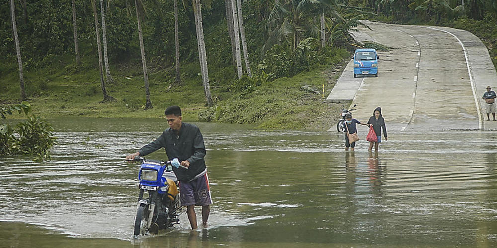 Bewohner überqueren eine überflutete Straße auf den Philippinen. Die Überflutungen wurden durch den Regen des Taifuns "Surigae" verursacht, der bisher mindestens sieben Menschenleben gefordert hat. Foto: Uncredited/AP/dpa