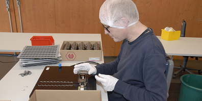 Adrian Lehmann bestückt Fläschchen von Estee Lauder mit Metallringen.