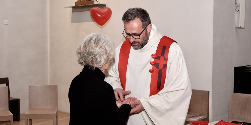 Pfarrer Andreas Schönenberger trägt etwas gut riechendes Öl auf die Hand einer Messebesucherin am Valentins-Gottesdienst in der Kirche Maria Himmelfahrt in Jona. 