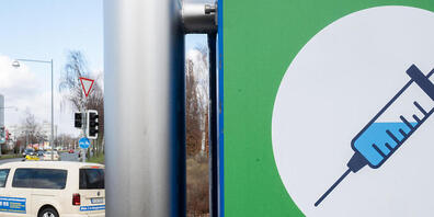 ARCHIV - Ein Schild mit einer Spritze hängt an der Zufahrt zum Impfzentrum auf dem Messegelände. Foto: Julian Stratenschulte/dpa
